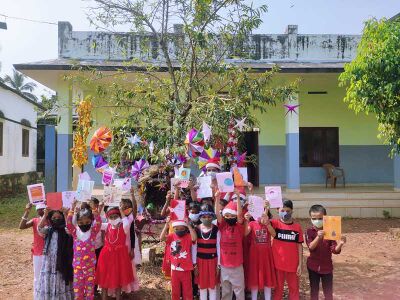 കുട്ടികൾ ആശംസാ കാർഡുകളുമായി പുൽക്കൂടിനു സമീപം.